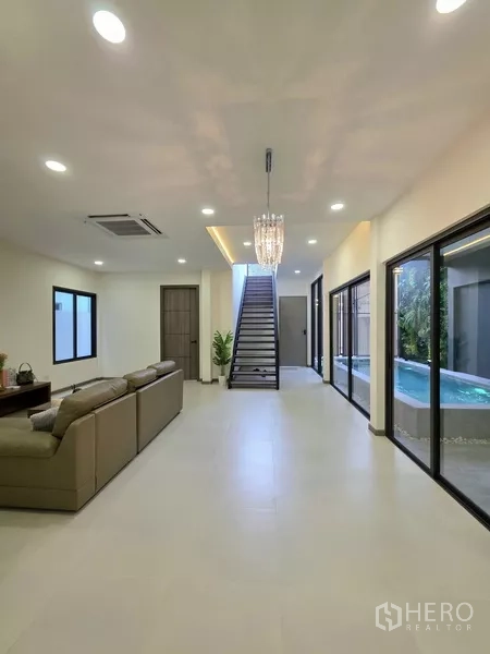 独立式住宅 出售在Khlong Toei, Bangkok - 狭长客厅，楼梯、大窗与泳池景观。