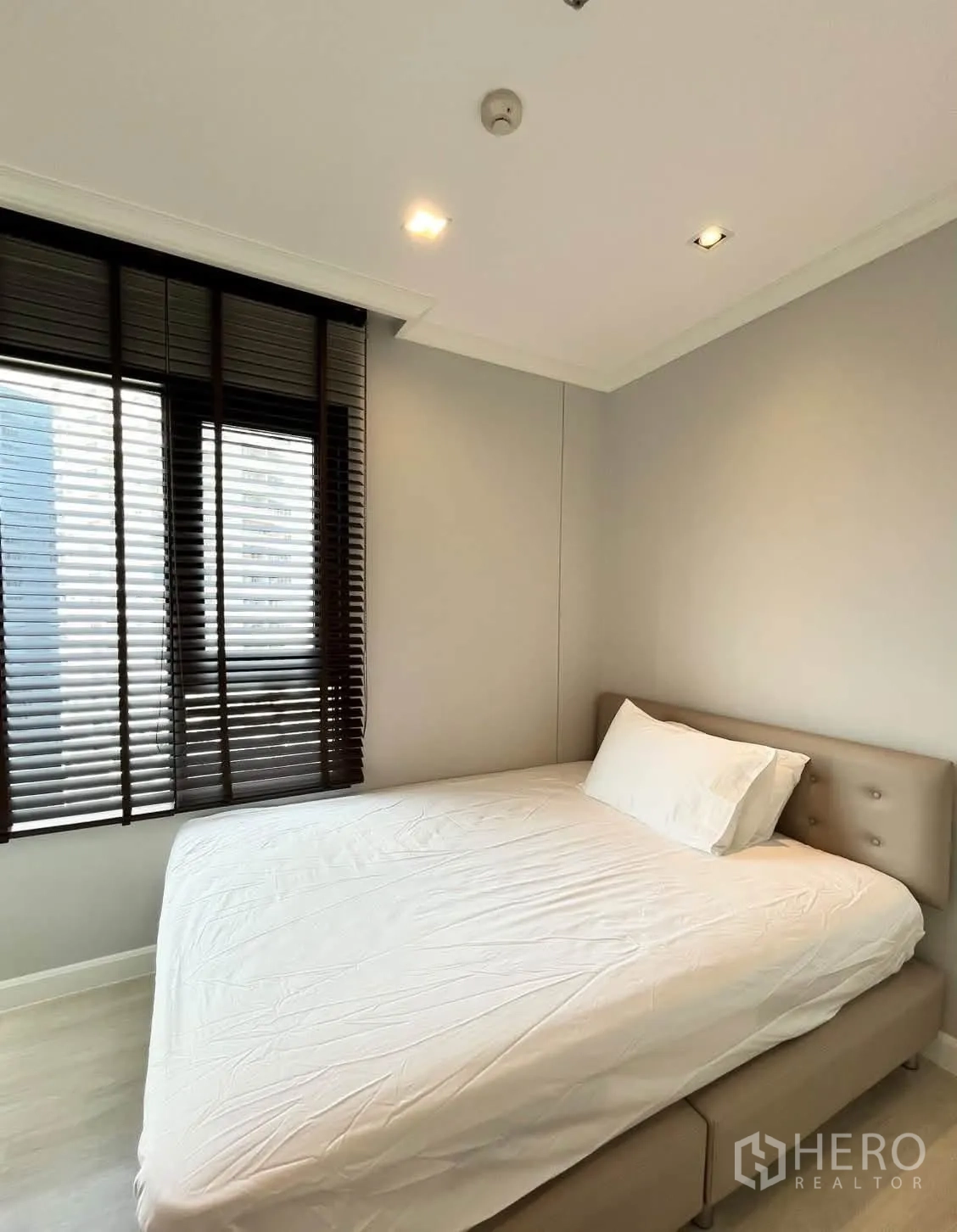 Condominium for rent in Pathum Wan, Bangkok - Bedroom with bed by the window and dark blinds.