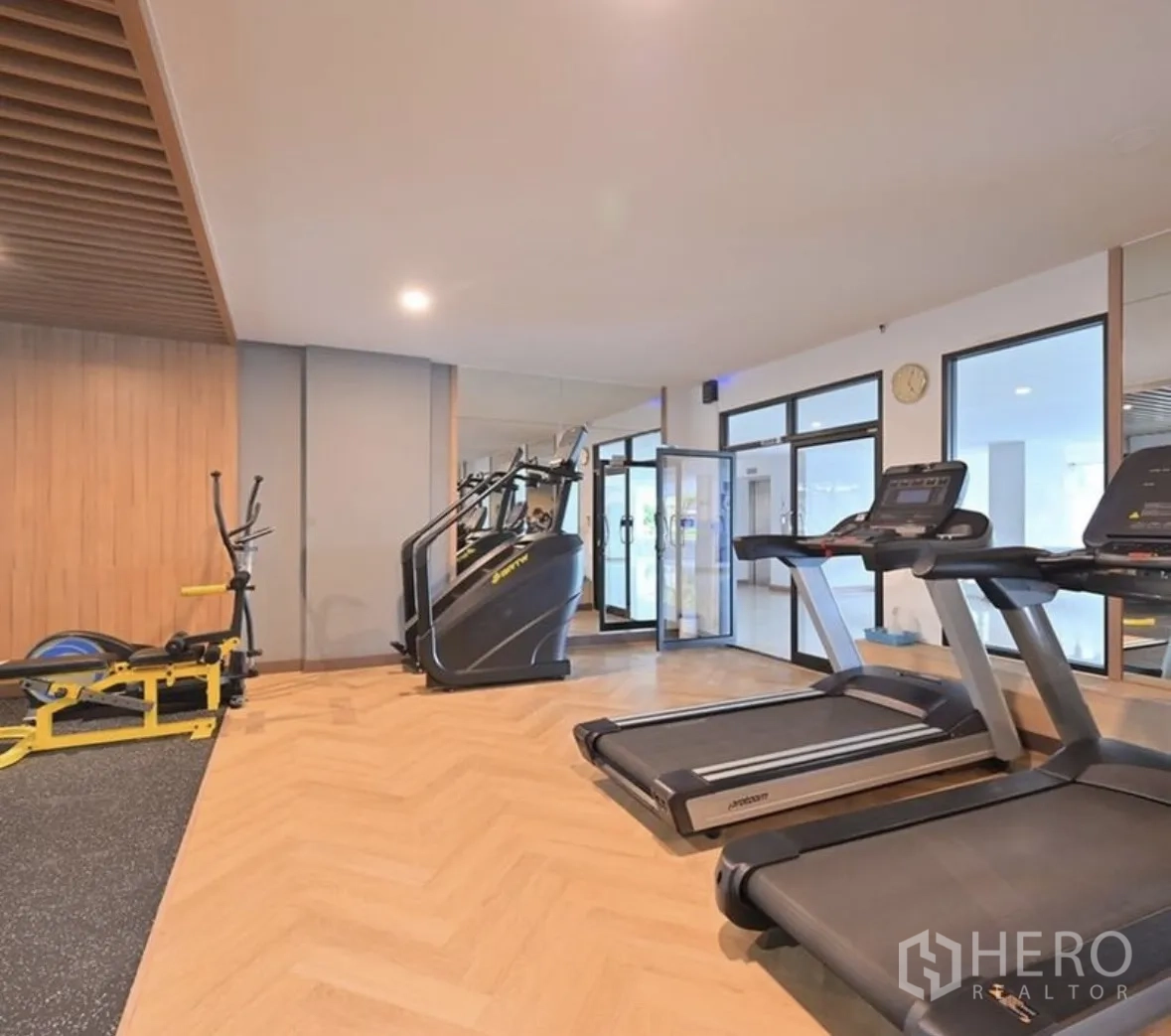 Condominium for rent or sale in Watthana, Bangkok - Gym area with treadmills and cardio machines beside glass doors.