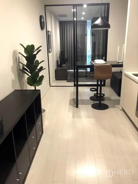公寓 出租或出售在Pathum Wan, Bangkok - 开放式过道配小厨房与吧台餐桌，玻璃隔断通向客厅