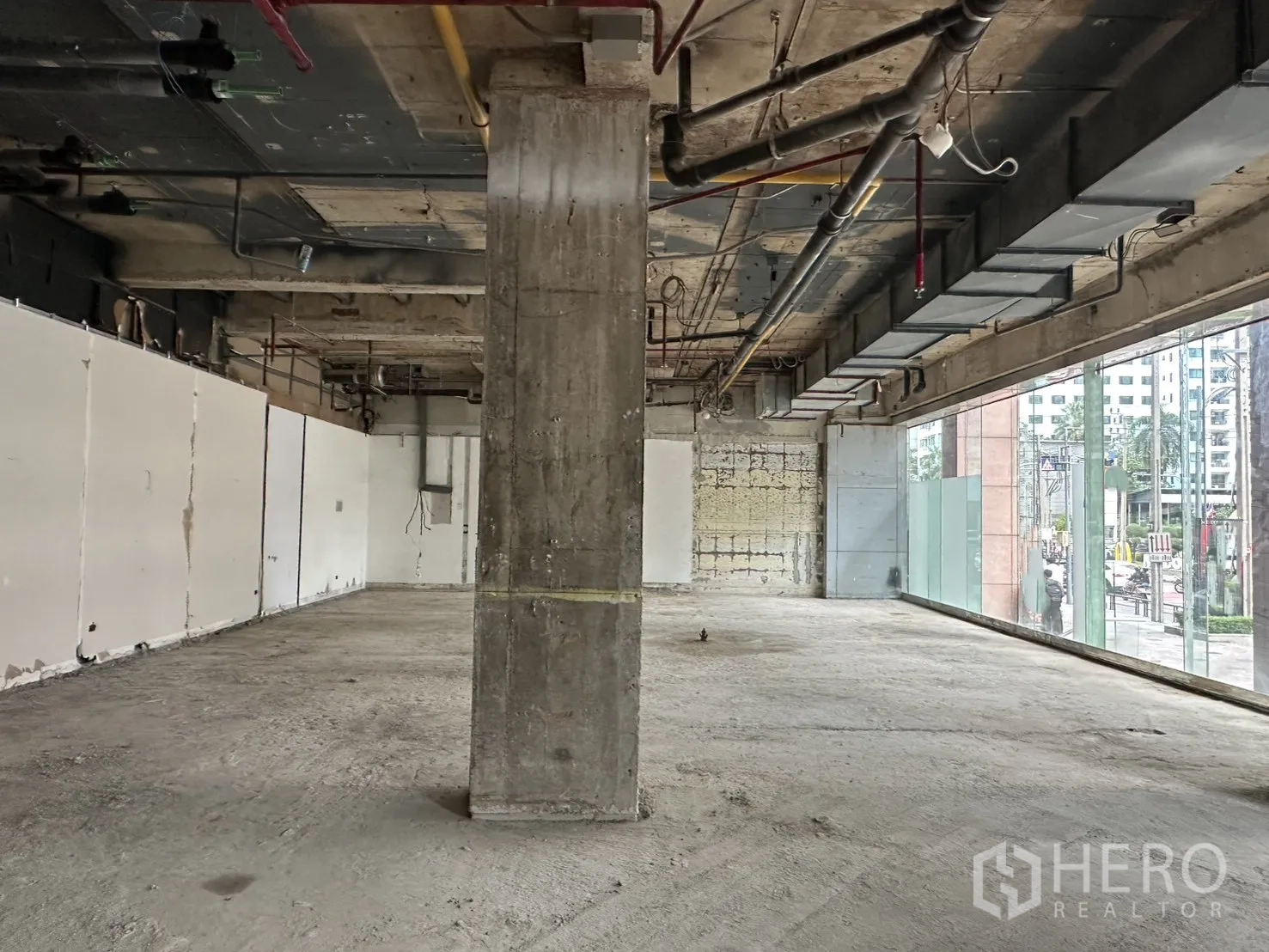 零售空间 for rent in Watthana, Bangkok - 毛坯零售室内，裸露吊顶、混凝土柱与临街落地玻璃。