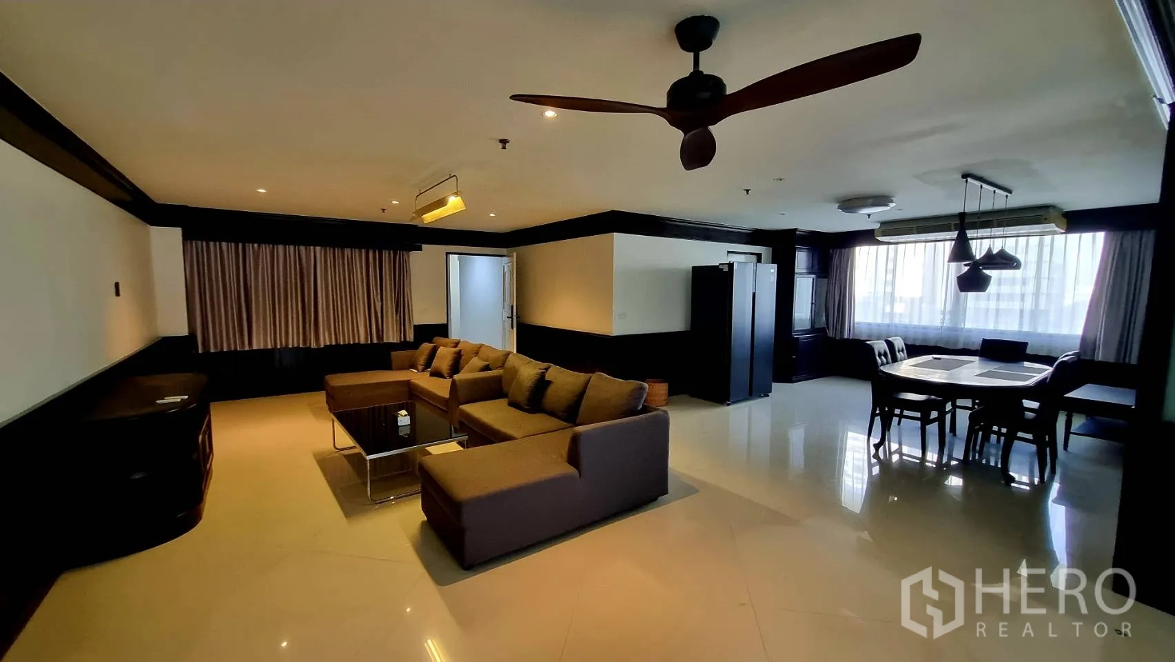Condominium for rent in Watthana, Bangkok - Spacious living and dining room with ceiling fan and picture windows.
