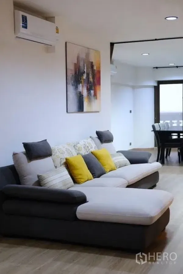 Condominium for rent in Bang Rak, Bangkok - Bright living room with sectional sofa, artwork and a view toward the dining area.