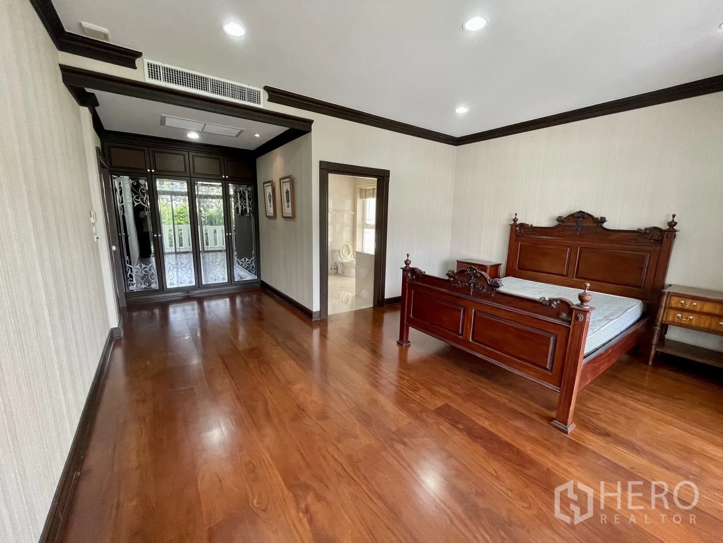 Detached House for rent in Chatuchak, Bangkok - Bedroom with teak wood floor, classic wooden bed and ensuite access.