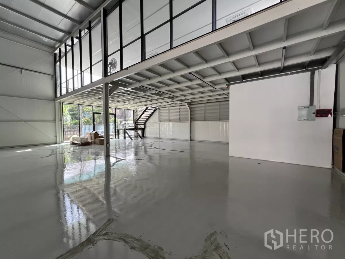 Warehouse for rent in Bang Na, Bangkok - Wide shot of warehouse with floor-to-ceiling windows, staircase, and open loading space.
