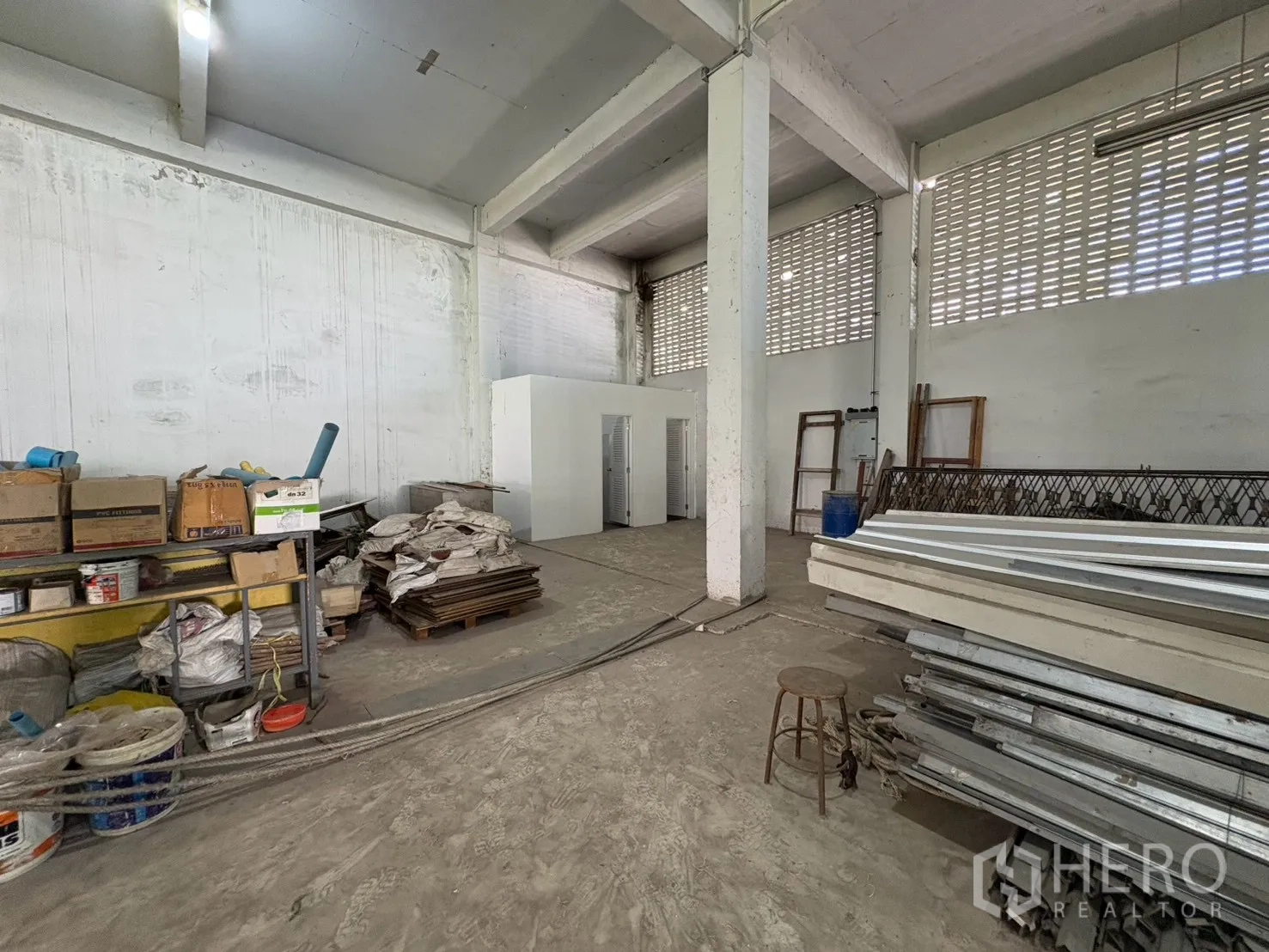 Warehouse for rent in Bang Na, Bangkok - Storage area with shelving, stacked materials, and small internal rooms.