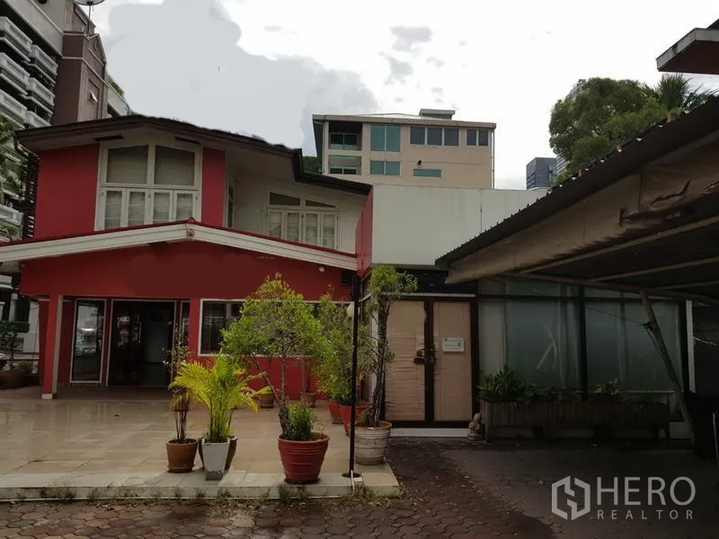 พื้นที่ขายปลีก ให้เช่าในWatthana, Bangkok - อาคารค้าปลีกสองชั้นสีแดงพร้อมลานหน้าบ้านและกระถางต้นไม้ในย่านวัฒนา