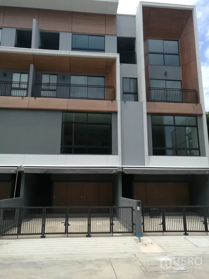 Townhouse for rent in Suan Luang, Bangkok - Modern three-storey townhouse facade with balconies and gated parking.