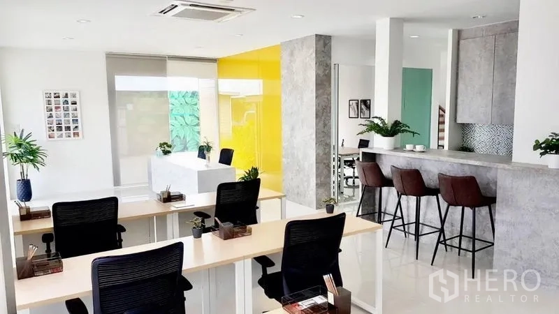 Warehouse for sale in Lam Luk Ka, Pathum Thani - Open‑plan office workspace with bar counter, desks and a yellow feature wall.
