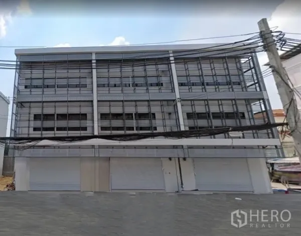 店屋 出租在Lat Phrao, Bangkok - 现代多层商住楼外立面，设多组卷帘门与栅格窗，临街位置。