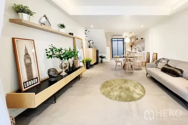 Townhouse for rent in Khlong Toei, Bangkok - Open-plan living and dining room flowing to the kitchen, with floating shelves and decor.