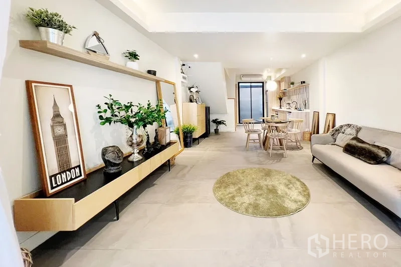 Townhouse for rent in Khlong Toei, Bangkok - Open-plan living and dining room flowing to the kitchen, with floating shelves and decor.