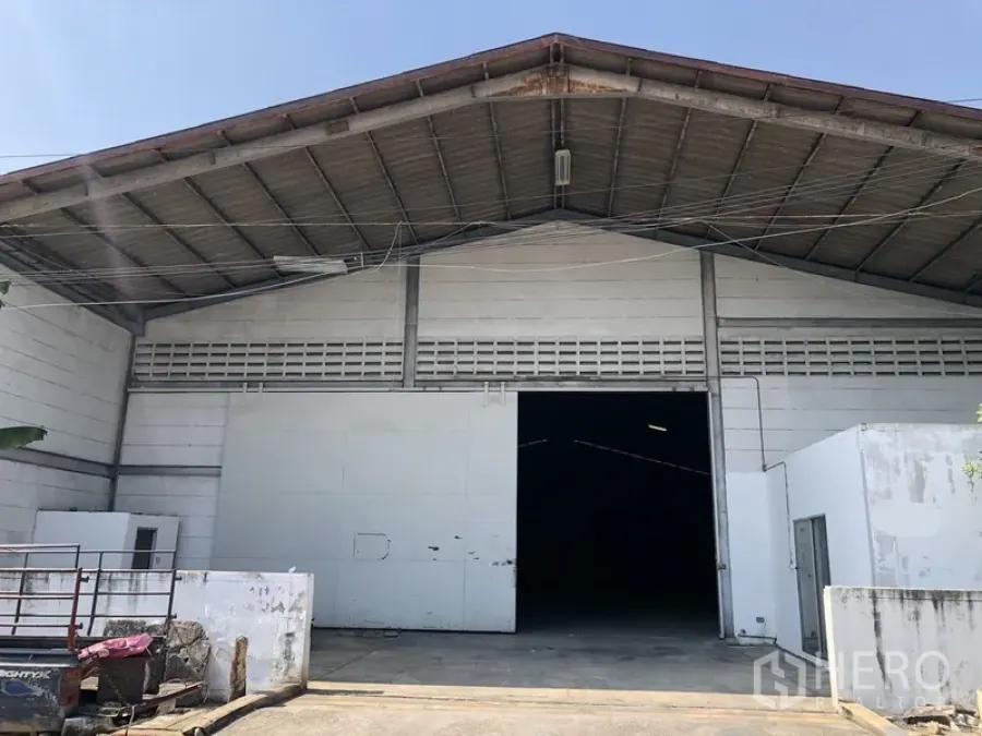货栈 出租在Khlong Luang, Pathum Thani - 仓库正立面，金属人字形高屋顶，超宽推拉门与混凝土装卸区。