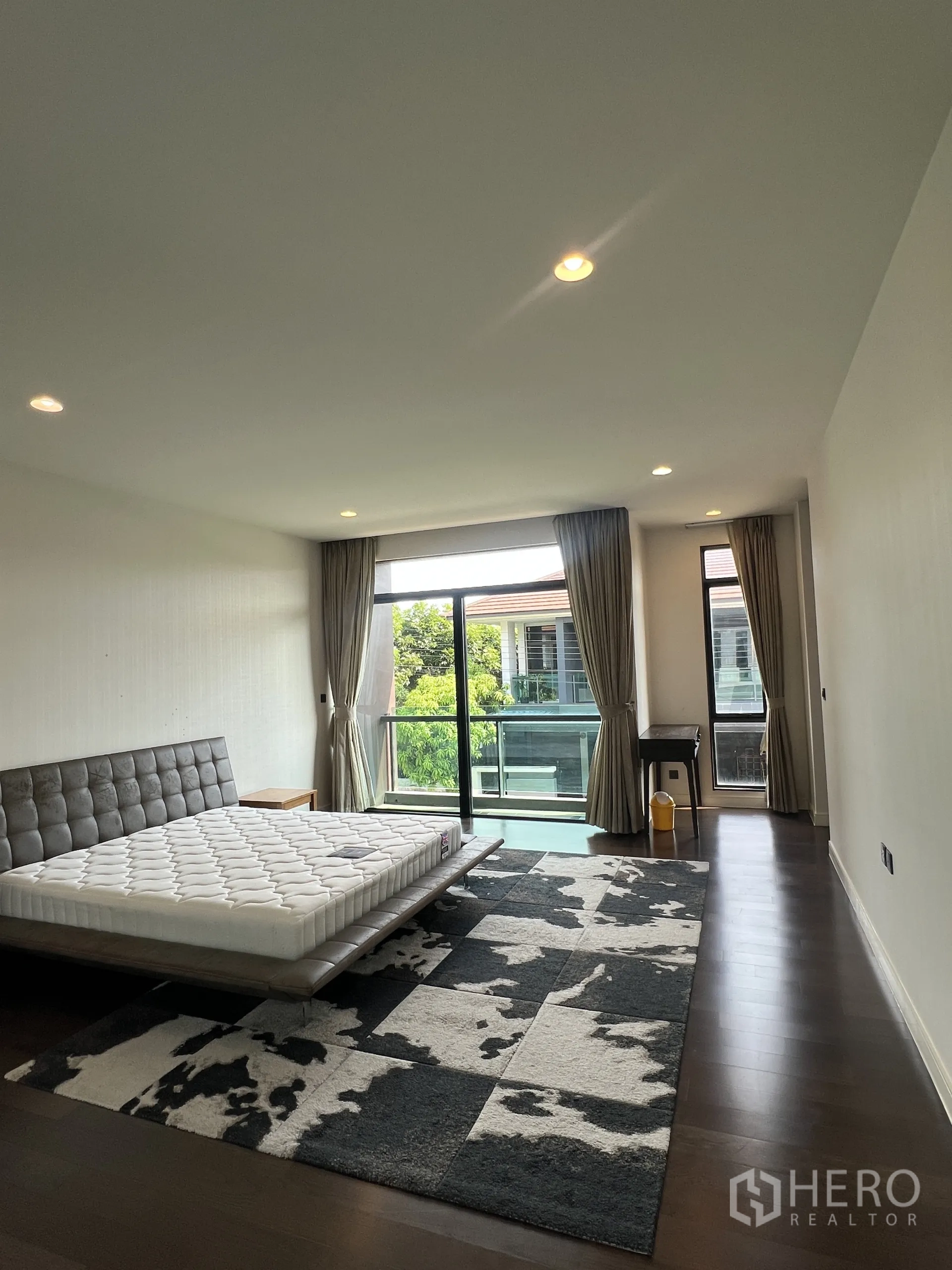 Detached House for rent in Bang Kapi, Bangkok - Master bedroom opening to a balcony through floor-to-ceiling glass with curtains.