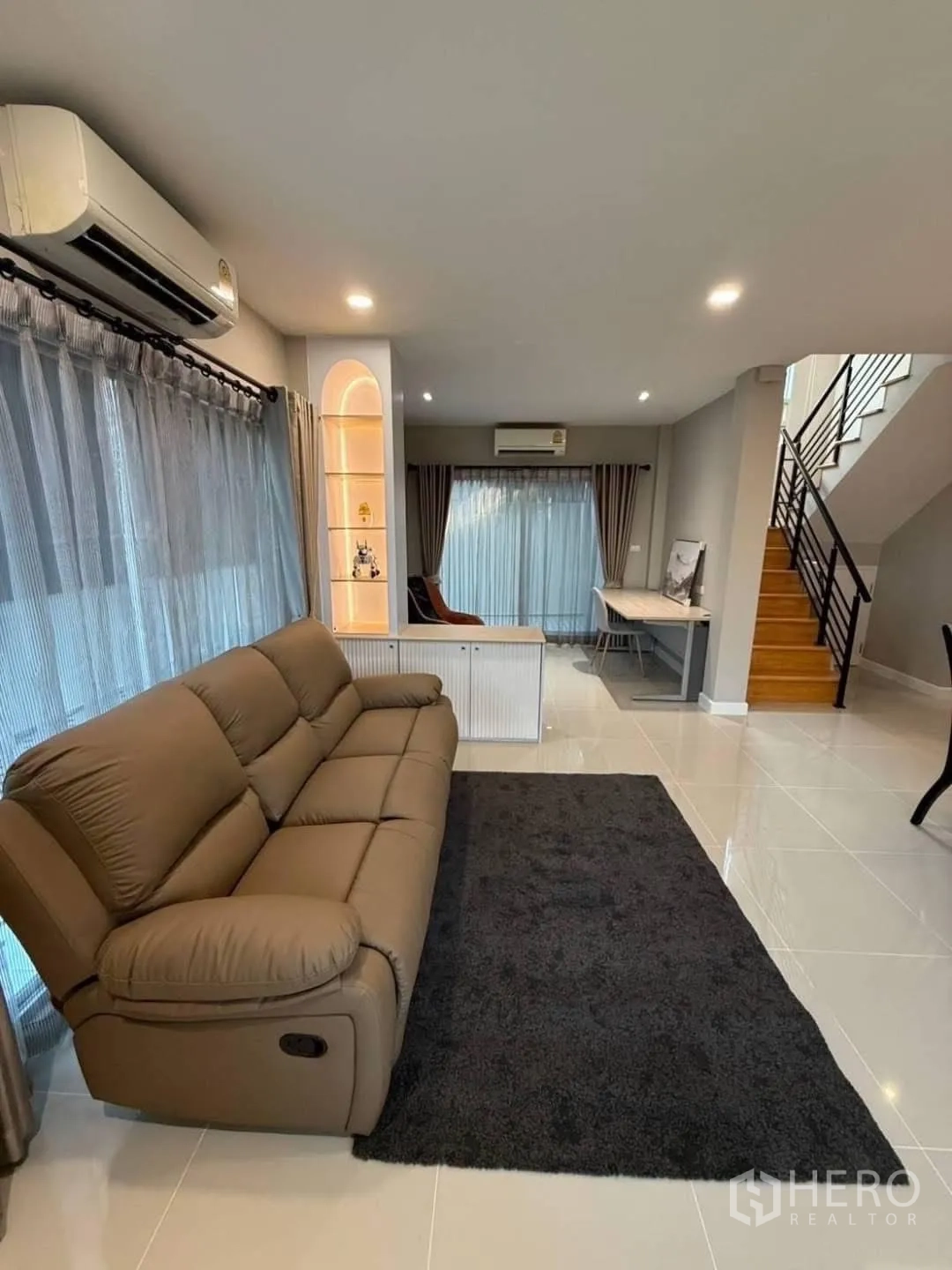 独栋房屋 for rent in Prawet, Bangkok - 宽敞客厅，棕色躺椅式沙发、深色地毯与楼梯