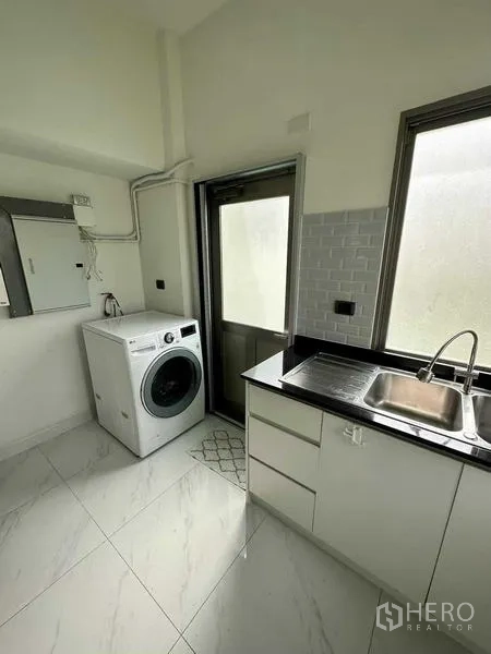Detached House for rent in Lat Krabang, Bangkok - Utility room with washing machine, stainless sink, black countertop and side door.