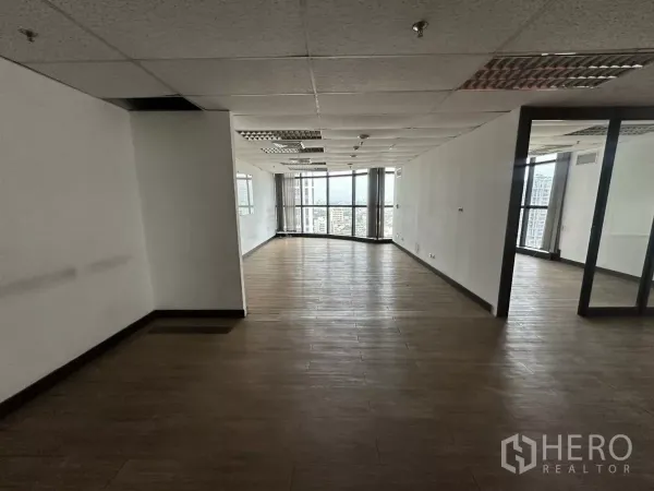 办公空间 出租在Watthana, Bangkok - 长条形开放工作区，白色墙面、吊顶照明，尽端大窗引入自然光。