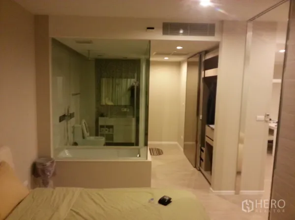 Condominium for rent or sale in Watthana, Bangkok - Bedroom with glass-walled bathroom, soaking tub and built-in wardrobe at The Room Sukhumvit 21