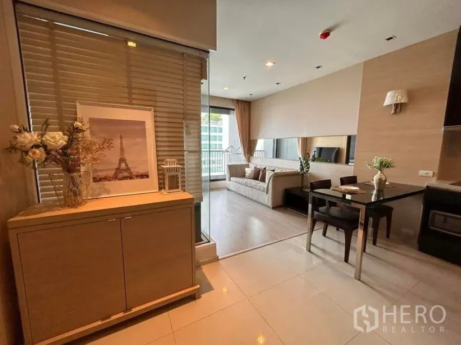 Condominium for rent or sale in Khlong Toei, Bangkok - Entry hall with storage cabinet opening to a light-filled living and dining area behind glass partition.
