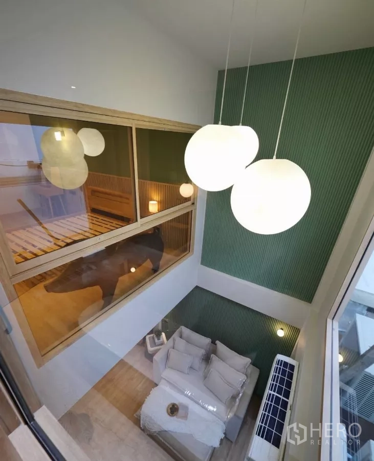 Townhouse for rent in Watthana, Bangkok - View from the mezzanine over the living area with globe pendant lights and a green accent wall.