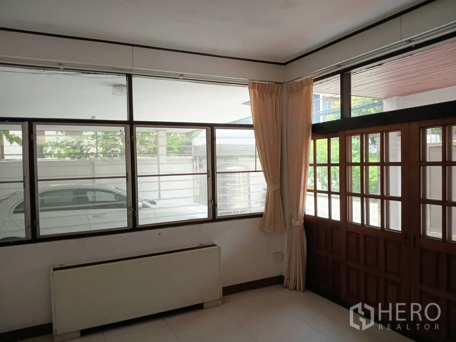 独栋房屋 for sale in Watthana, Bangkok - 起居区设大窗与木门，可望入户车道。