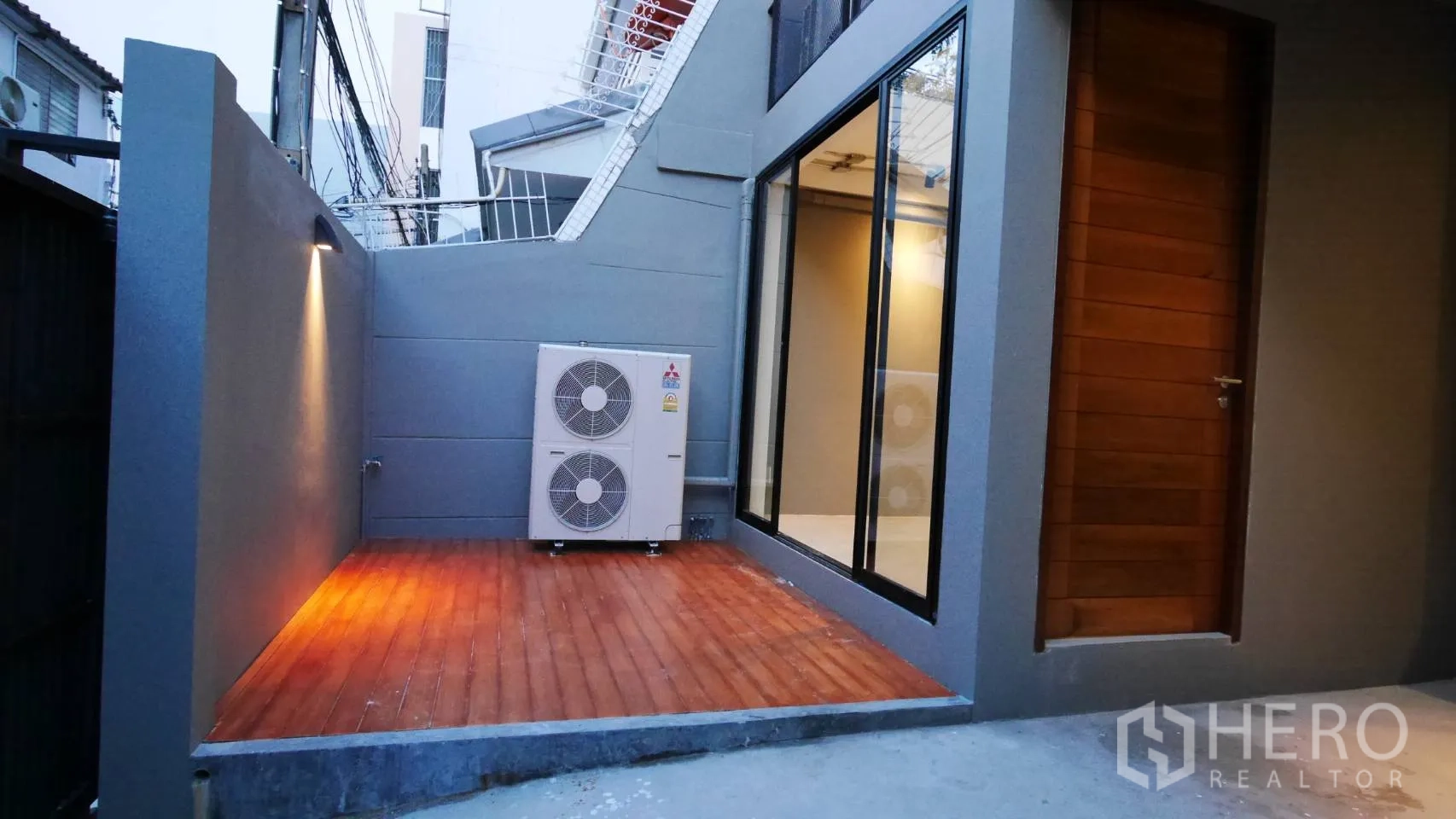 Townhouse for rent in Watthana, Bangkok - Private front patio with wood deck, exterior wall lighting and AC condensers.