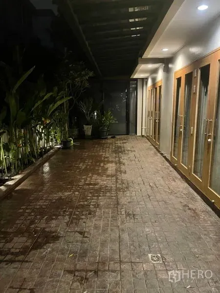 Townhouse for rent in Suan Luang, Bangkok - Outdoor walkway with canopy roof, potted plants and multiple glass doors leading inside.