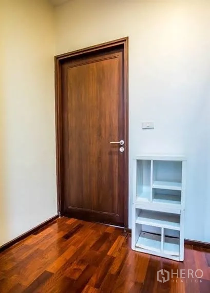 Condominium for rent or sale in Watthana, Bangkok - Small foyer with wooden door, white shelving and polished hardwood floor.