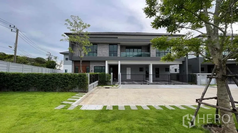 Detached House for sale in Bang Phli, Samut Prakan - Modern two-storey detached house in Bang Phli with wide driveway, balcony and landscaped lawn.