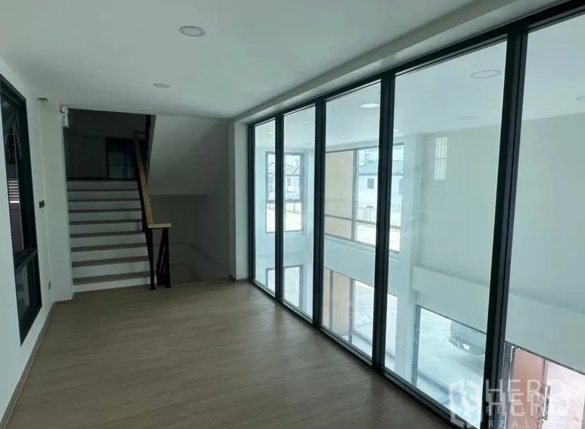 仓库 for sale in Lam Luk Ka, Pathum Thani - 玻璃幕墙办公室夹层，带楼梯与木纹地板，俯瞰装卸区。