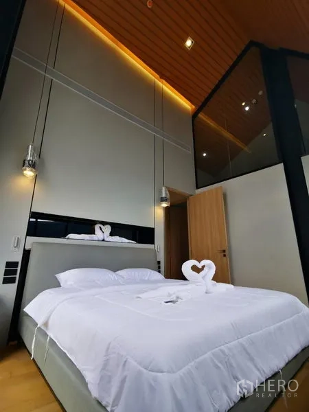 Apartment for rent in Khlong Toei, Bangkok - Master bedroom with high ceiling, pendant lights, and contemporary finishes.