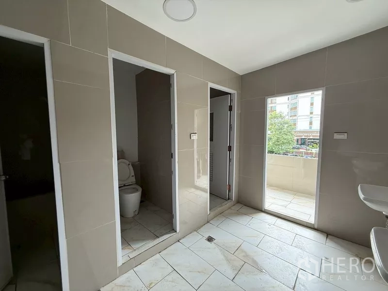 Shophouse for rent - Tiled restroom area with separate stalls and access to a small balcony.