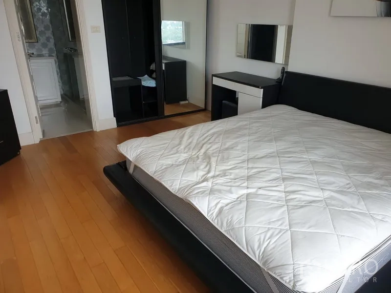 公寓 出租或出售在Khlong Toei, Bangkok - 宽敞卧室，木地板、大床、镜面衣柜，并有通往浴室的门。
