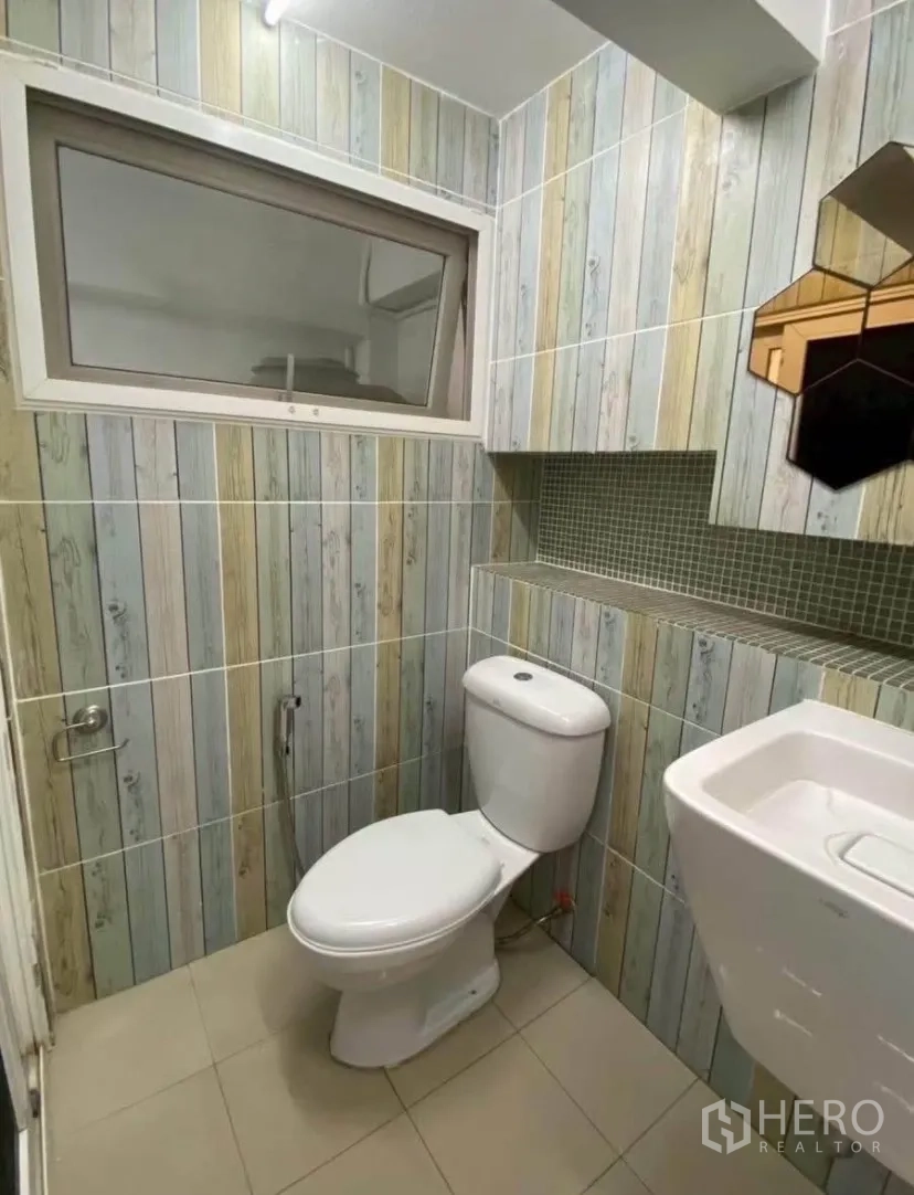 ทาวน์เฮาส์ for rent in Phra Khanong, Bangkok - ห้องน้ำขนาดกะทัดรัด ผนังลายไม้แนวตั้ง พร้อมหน้าต่าง โถสุขภัณฑ์ และอ่างล้างหน้า