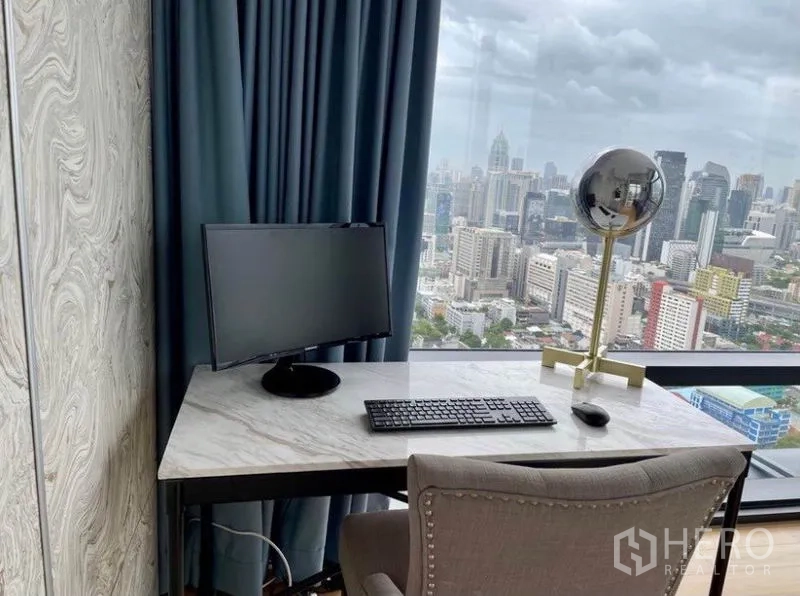 Condominium for sale in Ratchathewi, Bangkok - Work desk by a full-height window with computer setup and downtown views.