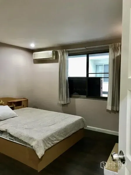 公寓 出租在Watthana, Bangkok - 卧室配双人床、壁挂空调与窗户，搭配浅色窗帘。