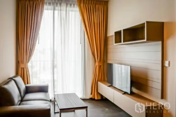 คอนโด ขายในWatthana, Bangkok - ห้องนั่งเล่นสว่างพร้อมโซฟาหนัง ชุดวางทีวี และหน้าต่างสูงจรดเพดานพร้อมผ้าม่าน