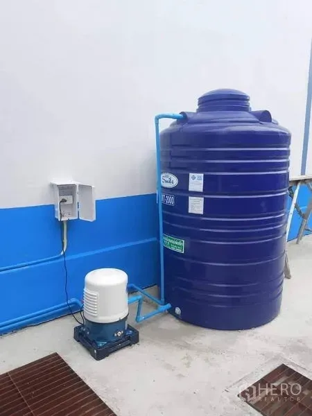 Warehouse for rent in Bang Phli, Samut Prakan - Large blue water storage tank with electric pump installed beside the warehouse wall.