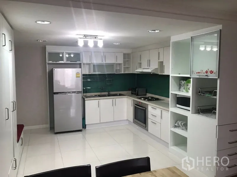 คอนโด ขายในWatthana, Bangkok - ห้องครัวเปิดโล่ง ตู้สีขาว เตาอบ ตู้เย็น และผนังกระจกสีเขียว
