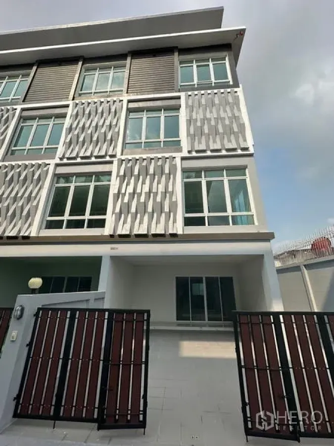 สำนักงานที่บ้าน ให้เช่าหรือขาย - ด้านหน้าอาคารโฮมออฟฟิศสไตล์โมเดิร์นหลายชั้น หน้าต่างบานใหญ่และรั้วหน้าบ้านสำหรับจอดรถ