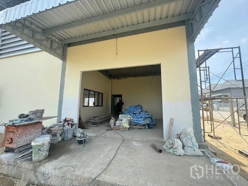 Warehouse for rent in Mueang Samut Prakan, Samut Prakan - Covered loading bay at the warehouse with open doorway and construction materials on the platform.