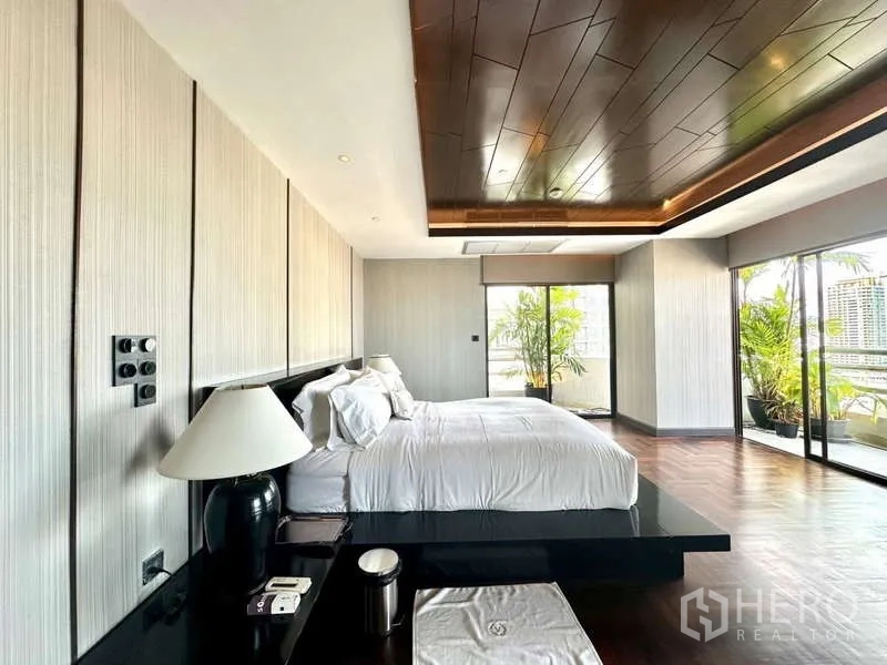 Condominium for rent in Watthana, Bangkok - Master bedroom with floor-to-ceiling sliding doors opening to terrace with plants.