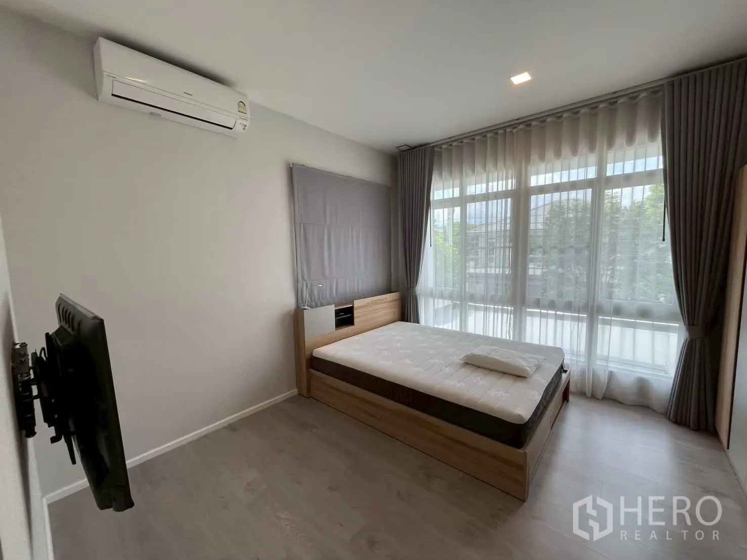 Detached House for rent in Prawet, Bangkok - Bright bedroom with large corner windows, bed and wall-mounted air conditioner.