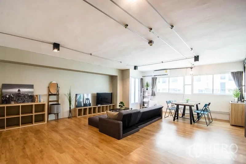 Home Office for rent in Phaya Thai, Bangkok - Wide loft-style room with wood flooring, TV console and ample natural light from multiple windows.