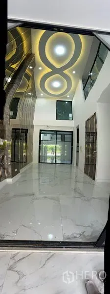 Townhouse for rent or sale in Yan Nawa, Bangkok - Long view of marble-tiled living area leading to glass sliding doors and a mirrored feature wall.