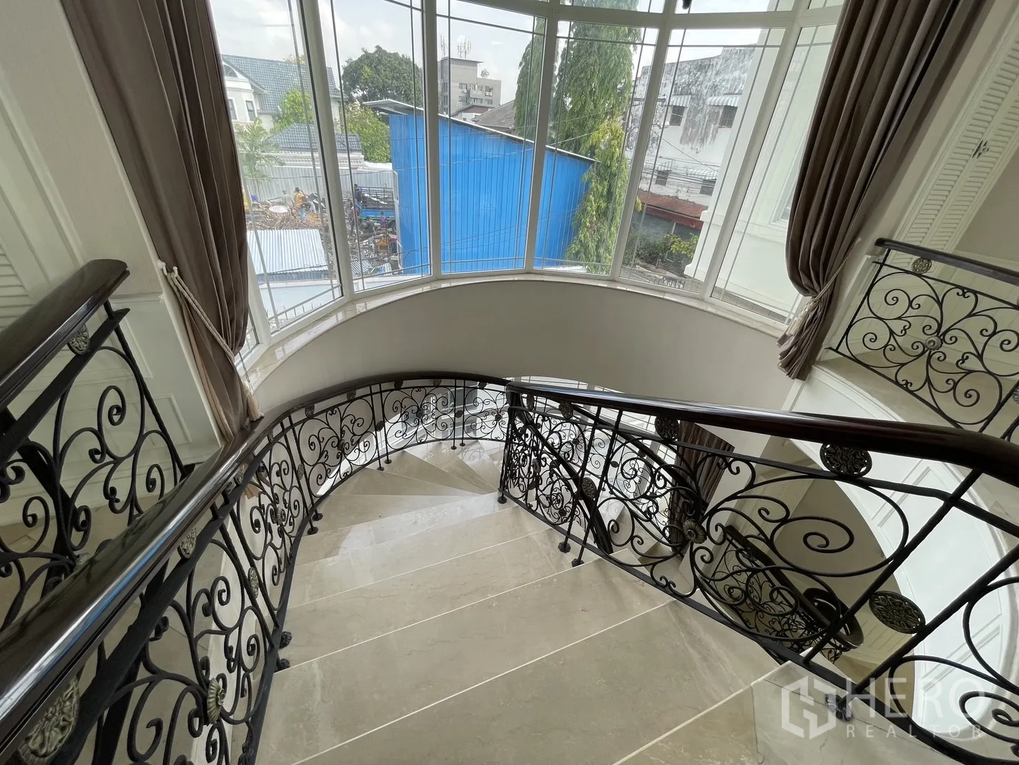 Detached House for rent in Chatuchak, Bangkok - Sweeping staircase beside tall bay windows with drapes and abundant natural light.