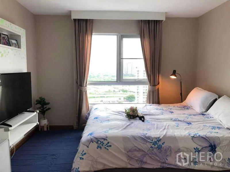 คอนโด ขายในHuai Khwang, Bangkok - ห้องนอนมาสเตอร์สว่าง หน้าต่างบานใหญ่ วิวเมือง ทีวี และโคมไฟหัวเตียง