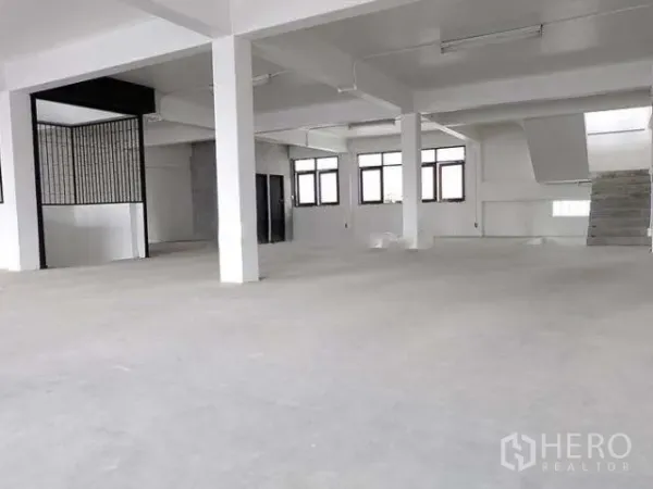 Home Office for sale in Khlong Toei, Bangkok - Spacious open-plan floor with white columns, windows and unfinished concrete floor.