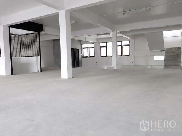 Home Office for sale in Khlong Toei, Bangkok - Spacious open-plan floor with white columns, windows and unfinished concrete floor.