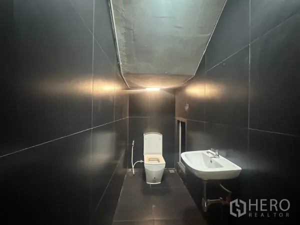 带办公室的家 出租在Pathum Wan, Bangkok - 黑色瓷砖卫浴，坐便与挂墙式洗手盆，顶高较低。